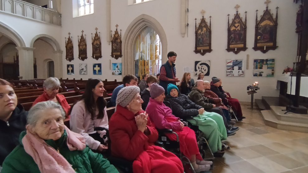 BewohnerInnen, SchülerInnen, Lehrer, ehrenamtlich Tätige beim Beten in der Kirche.