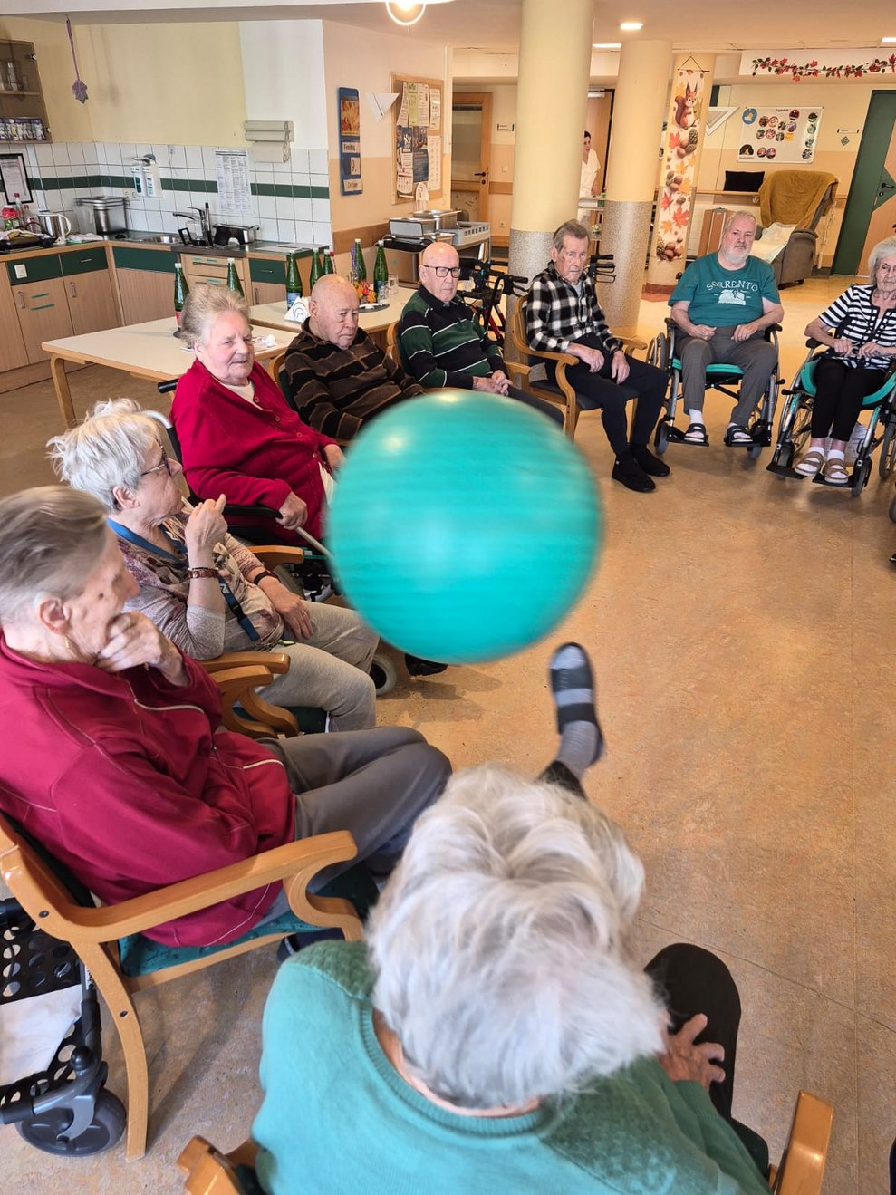 Peziball in der Luft. Bewohnerin versucht Peziball mit ihrem Fuß zu treffen.