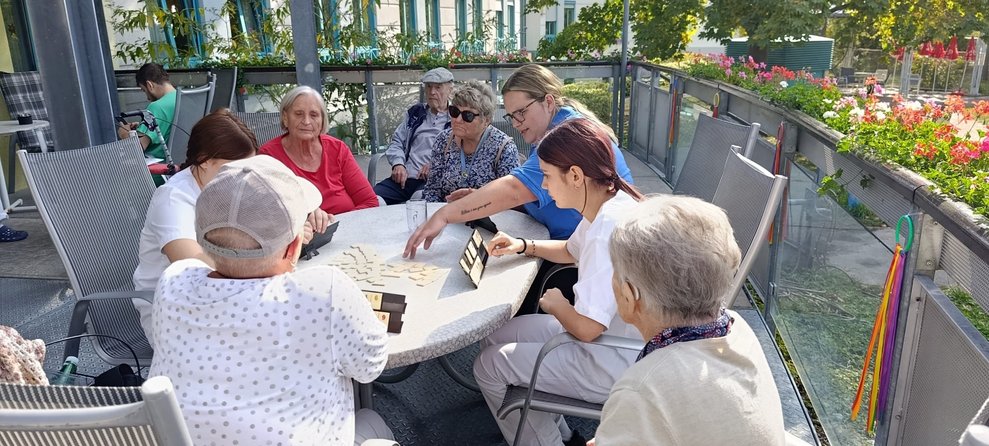 Bewohnerinnen, ehrenamtlich Tätige und zwei Praktikantinnen beim "Rummikub" spielen.