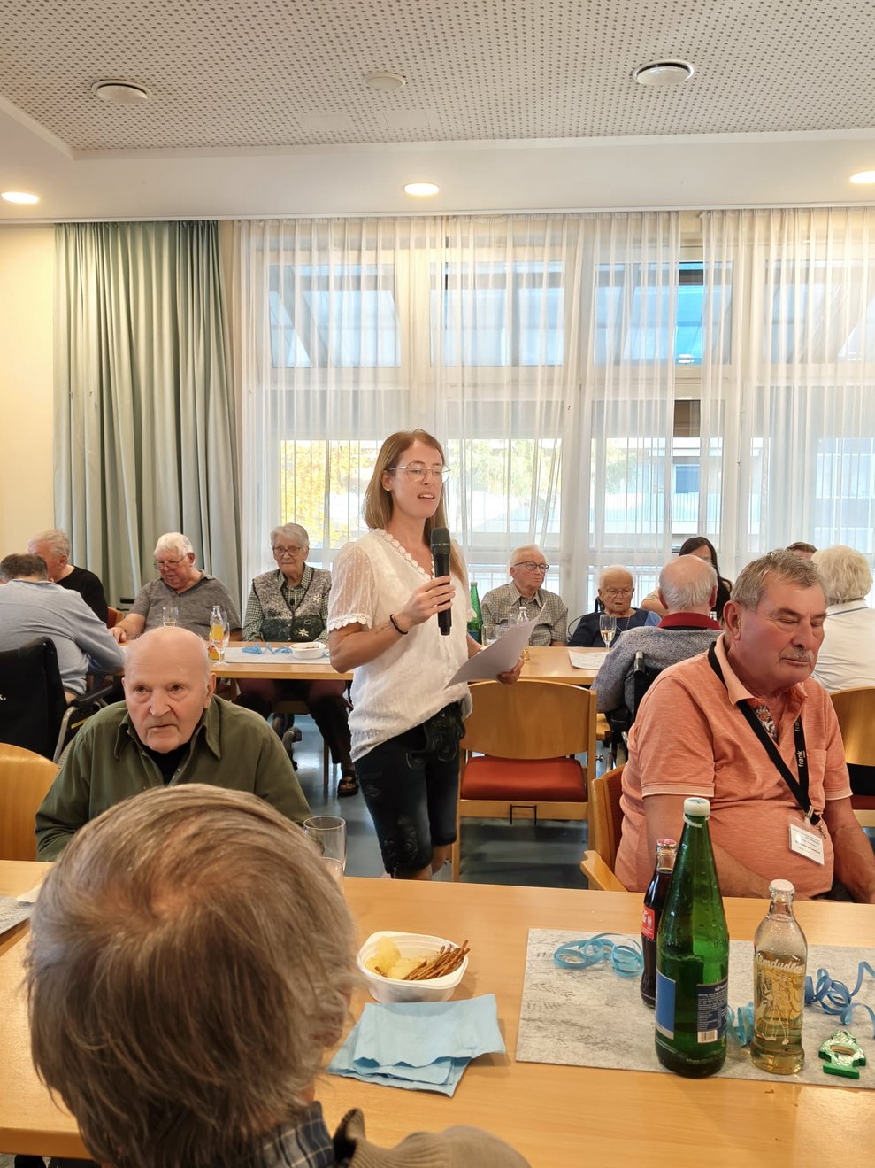 Personen beim Oktoberfest. Alltagsbegleiterin hält Zettel und Mikrofon in der Hand und spricht ins Mikrofon.