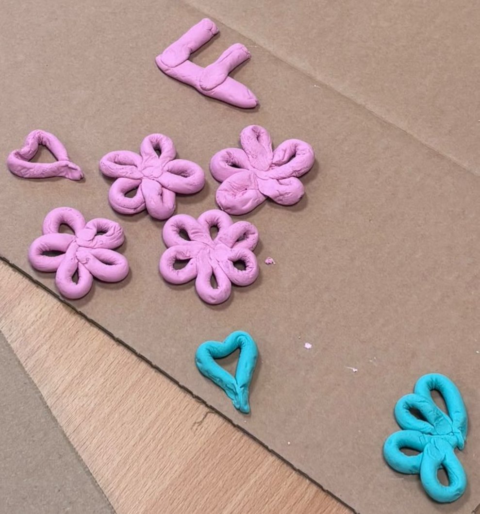 Buchstabe, Blüten, Herz aus lila und blauem Ton.