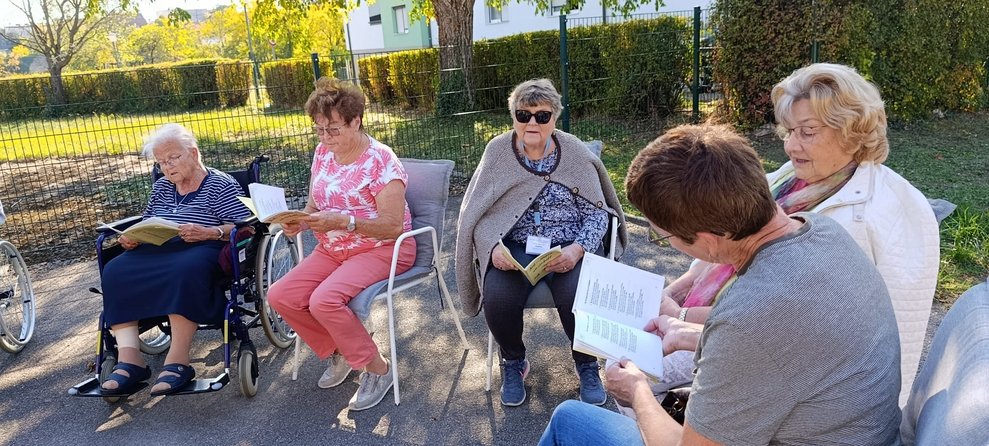 Bewohnerinnen und ehrenamtlich Tätige beim Singen. Liederbuch in den Händen.