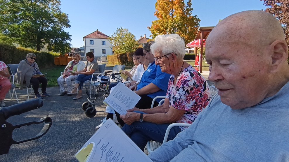 Personen beim Singen. Liederbuch wird in den Händen gehalten.