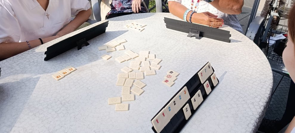 Das Spiel "Rummikub". Spielsteine liegen auf Tisch. In der Spielhalterung sind Spielsteine aufgestellt.