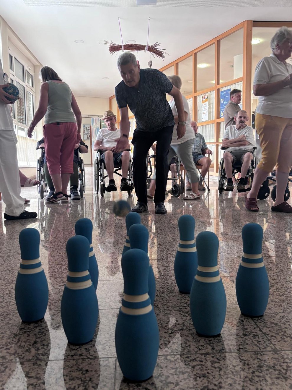 Stehende Bewohner beim Kegeln. Kegelball in der Luft.