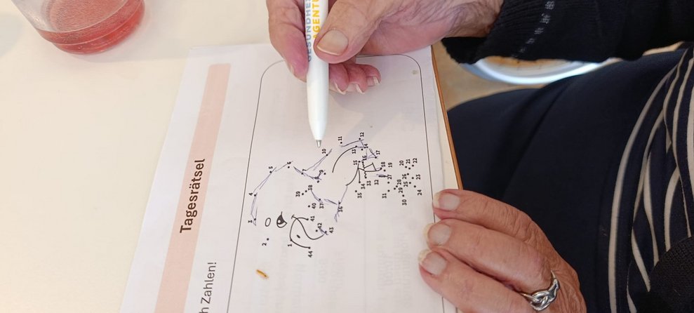 Hand hält Stift und zieht eine Linie von Punkt zu Punkt