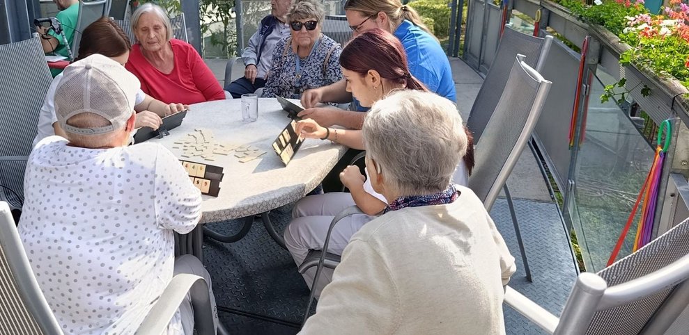 Bewohnerinnen, ehrenamtlich Tätige und zwei Praktikantinnen beim "Rummikub" spielen.