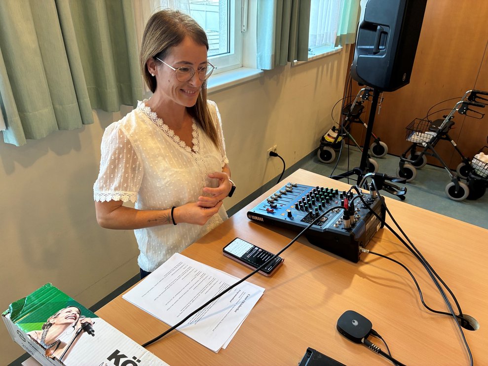 Alltagsbegleiterin steht bei Musikanlage.