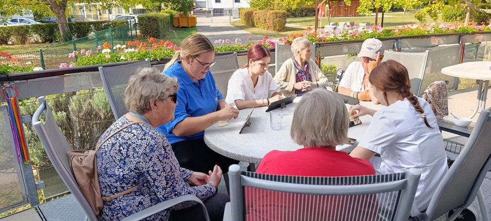 Bewohnerinnen, ehrenamtlich Tätige und zwei Praktikantinnen beim "Rummikub" spielen.