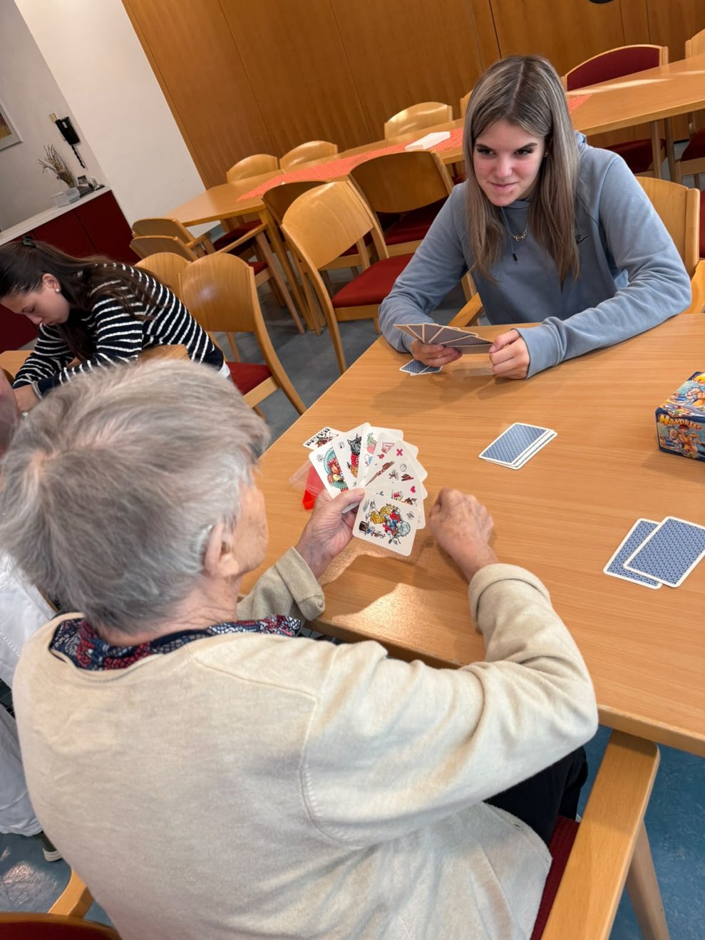Bewohnerin und Schülerin beim "Schwarzen Peter" spielen.