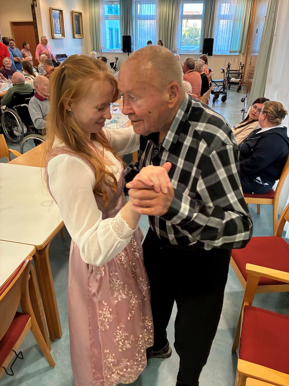Mitarbeiterin und Bewohner tanzen zusammen.