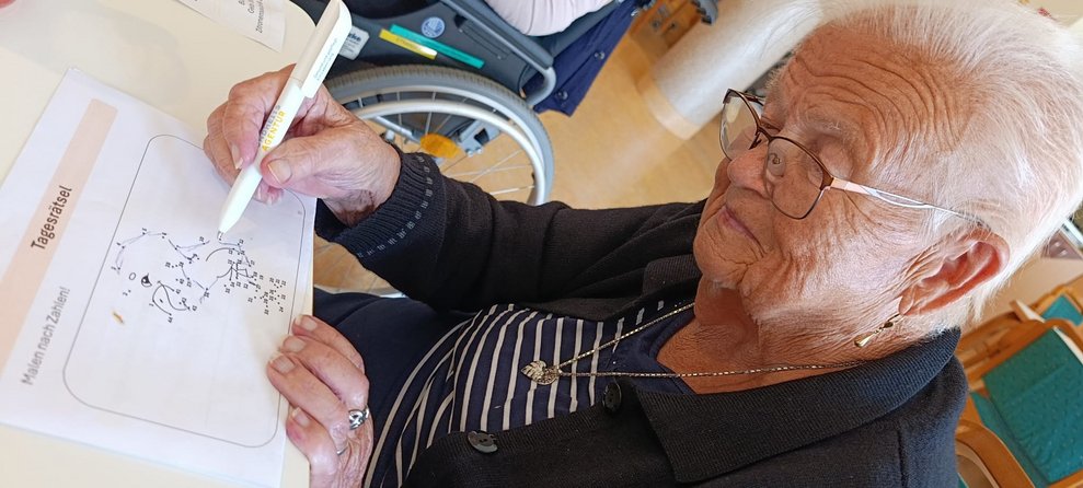 Bewohnerin hält Stift und zieht eine Linie von Punkt zu Punkt