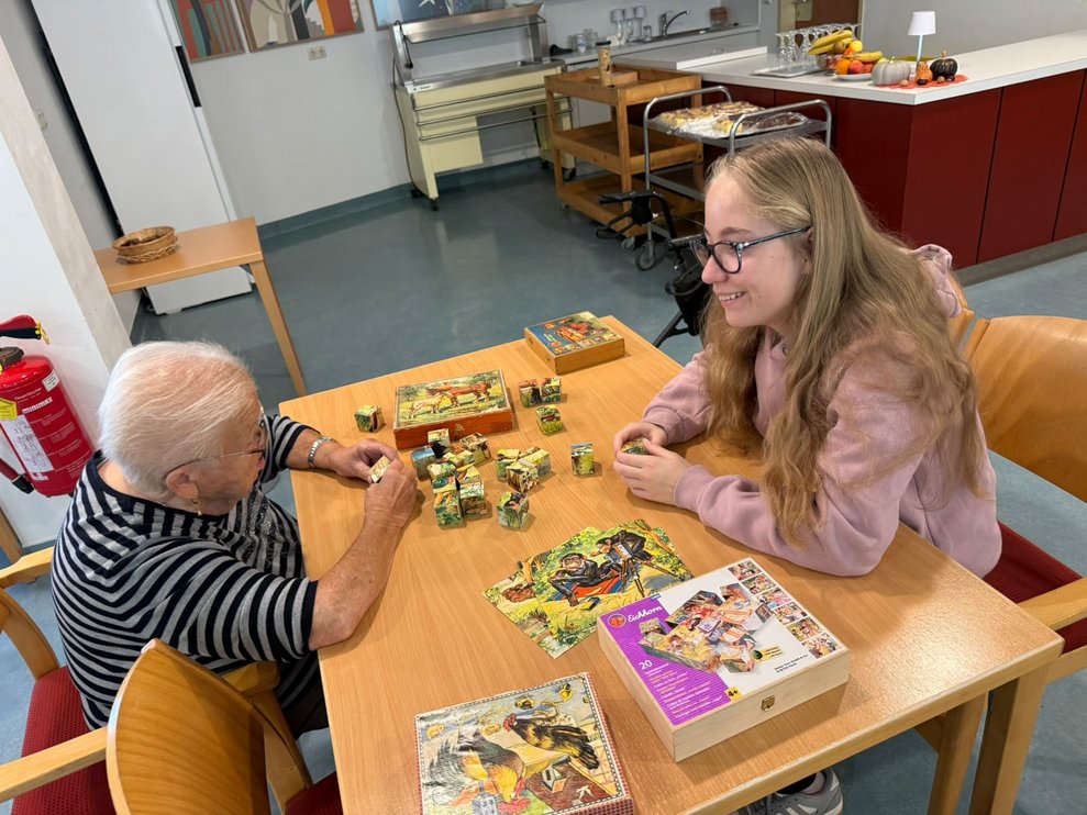 Bewohnerin und Schülerin setzen Würfelpuzzle zusammen.